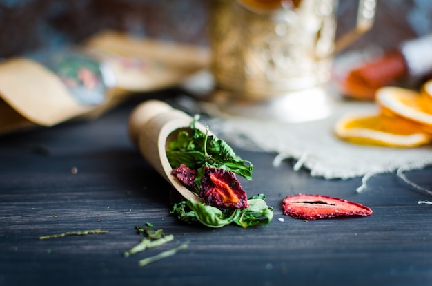 Groene thee muntblaadjes met aardbei in een houten lepel en kopje thee