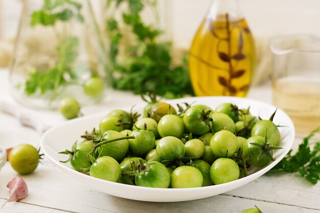 Groene tomaten in een witte kom. Voorbereiding voor beitsen.