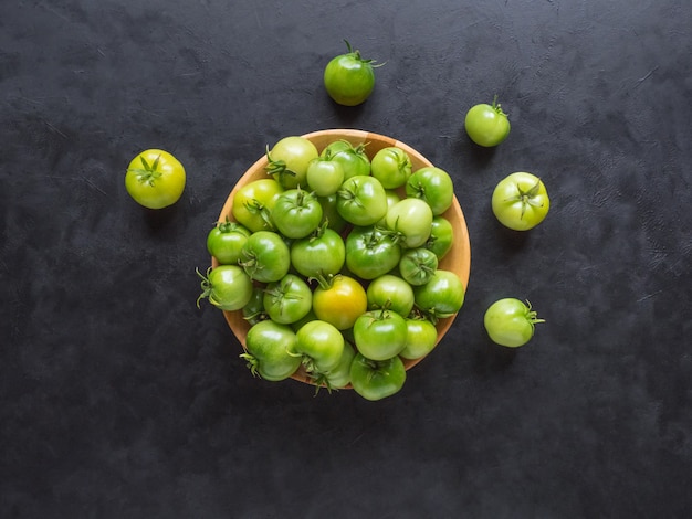 Groene tomaten op een zwarte tafel. Bovenaanzicht