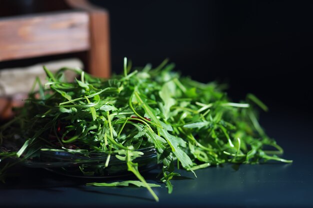 Groene vegan salade van groene bladeren mix en groenten. Verse rucola bladeren in een vergiet. Zwarte achtergrond.