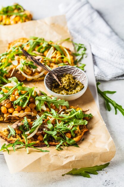 Groene veganistische pizza met pesto, kikkererwten, champignons en rucola.