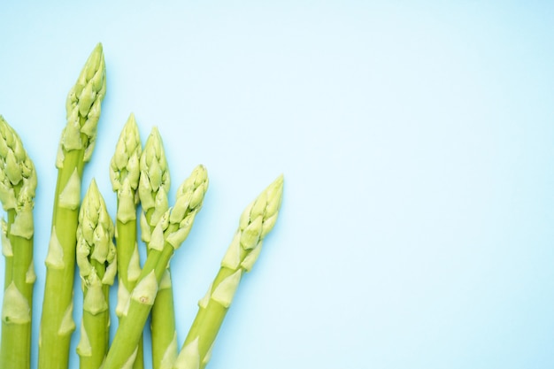 Groene verse asperges op blauwe ondergrond, ruimte voor tekst. Detailopname