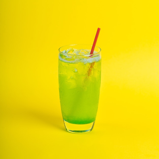 Groene verse cocktail smoothie sap in glas met ijs op gele achtergrond vitamine drankje detox ice