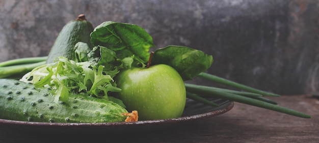Groene verse groenten: komkommer, sla, ui, avocado, appel op oude achtergrond