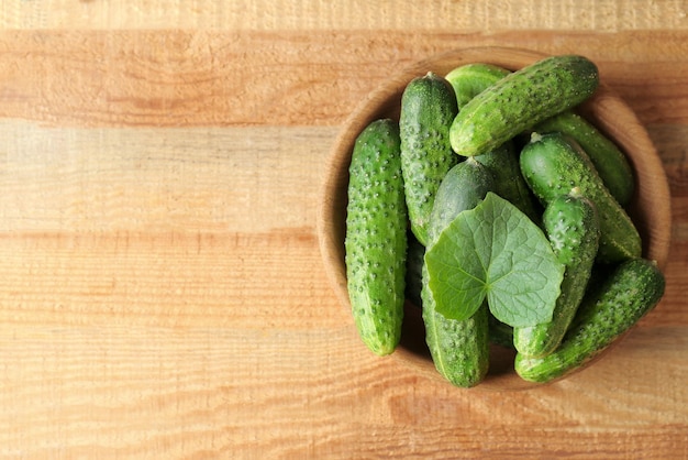 Groene verse komkommers in kom op houten tafel