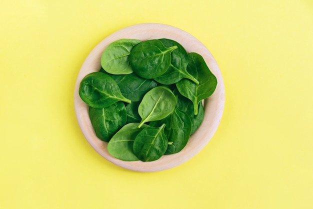 Groene verse vegetarische saladebladeren op houten plaat op geel