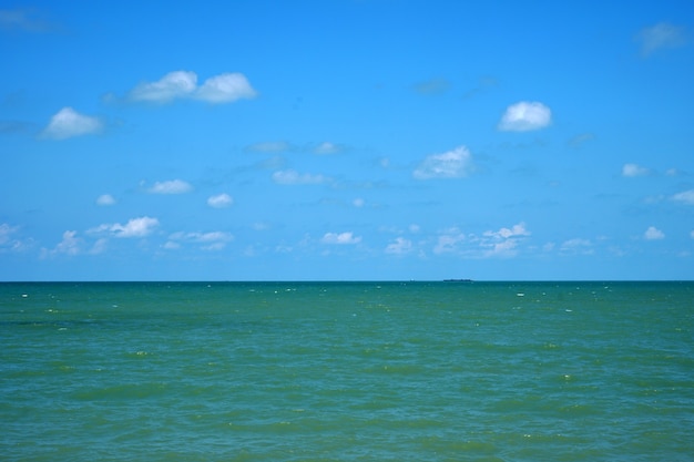 Groene zee en blauwe lucht met wolkenachtergronden