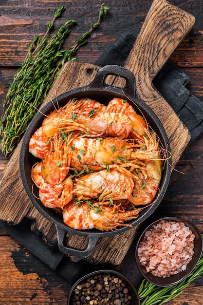 Groenlandse Garnalen Garnalen in een pan koken met tijm en rozemarijn. Donkere houten achtergrond. Bovenaanzicht.