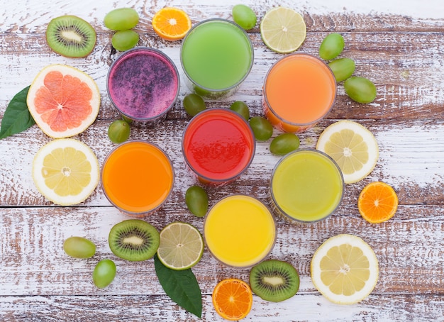 Groente- en citrussappen. Stukken groenten en fruit op houten bureau. Ongebruikelijk bovenaanzicht