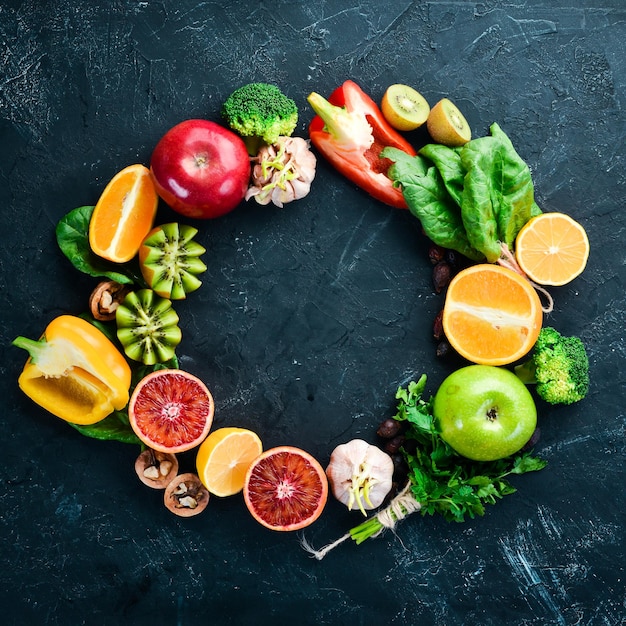 Groenten en fruit die vitamine C bevatten Sinaasappel citroen appel rozen knoflook broccoli appel kiwi spinazie Bovenaanzicht Op een zwarte stenen achtergrond