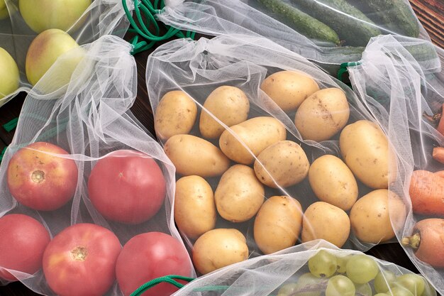 Groenten en fruit in herbruikbare milieuvriendelijke zakken op houten achtergrond. zero waste.