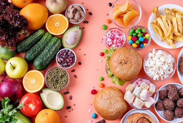 Groenten en fruit versus snoep en fastfood bovenaanzicht plat lag op oranje achtergrond