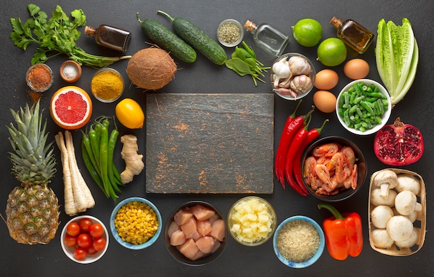 Groenten en ingrediënten rond een houten bord, bovenaanzicht