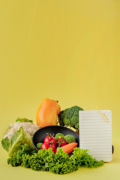 Groenten en notebook met kopie ruimte op gele achtergrond Bio Gezonde voeding Biologische groenten op gele achtergrond