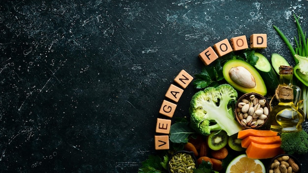 Groenten, fruit en noten, avocado, broccoli, pistachenoten, pompoen, gedroogd fruit, selderij, komkommer en kiwi De inscriptie VEGAN FOOD Bovenaanzicht Rustieke stijl