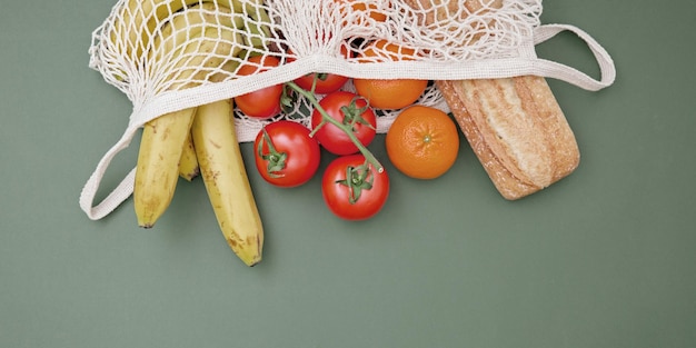 Foto groenten fruit pasta in een glazen pot en brood in een boodschappentas op een groene achtergrond het concept van leven en winkelen zonder afval geen plastic kopieer ruimte bovenaanzicht webbanner