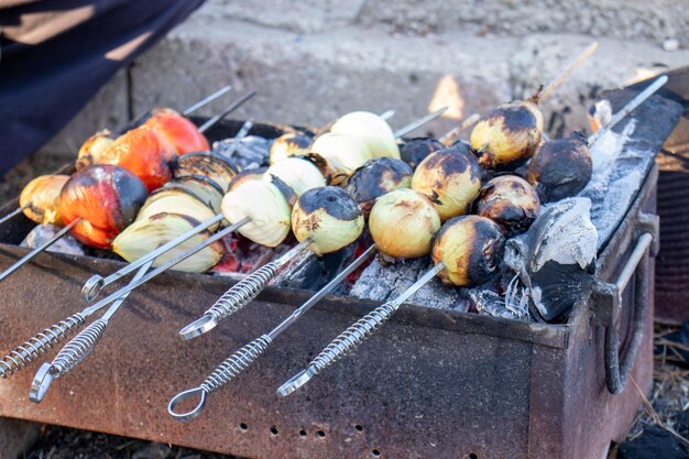 groenten grillen op houtskool met uien en tomaten met vuur en rook