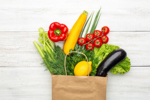 Groenten in een papieren zak op een witte houten ondergrond. Winkelen in een supermarkt of markt.