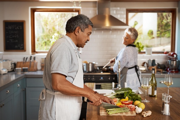 Groenten koken en oude man met vrouw in keukengeluk en gezonde hechtingstijd in huis Huwelijksliefde en eten senior koppel met maaltijdbereiding voor groentediner met pensioen wellness