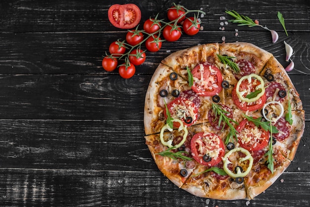 Groenten, paddestoelen en tomatenpizza op een zwarte houten achtergrond. het kan als achtergrond worden gebruikt