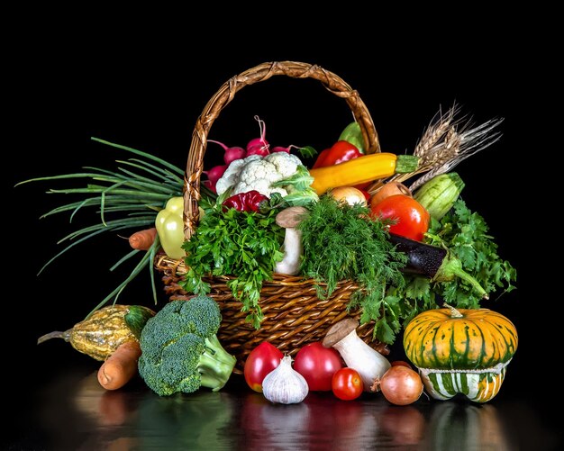 Groenten tot een rieten mand ingrediënten voor het koken van verschillende gerechten op een zwarte achtergrond