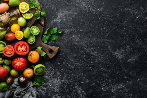 Groenten verse gekleurde tomaten op een zwarte stenen achtergrond bovenaanzicht vrije ruimte voor uw tekst