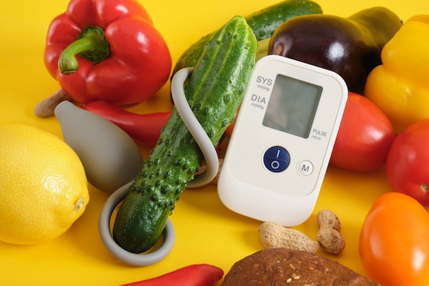 Groententonometer op een gele achtergrondexemplaarruimte, digitale bloeddrukmeter. goed en gezond voedingsconcept