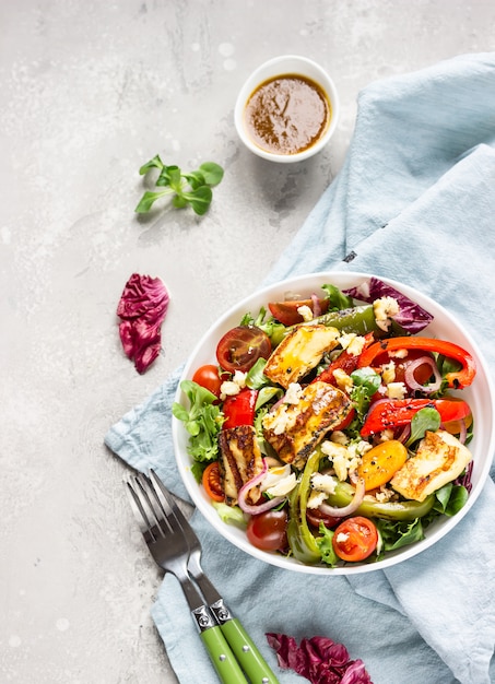 Groentesalade cherrytomaatjes, gebakken peper, salademix en ui met gegrilde haloumi-kaas