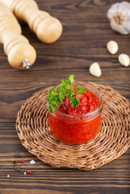 Groentesalade lecho van tomaten, paprika, uien, knoflook en kruiden in een glazen pot op een tafel