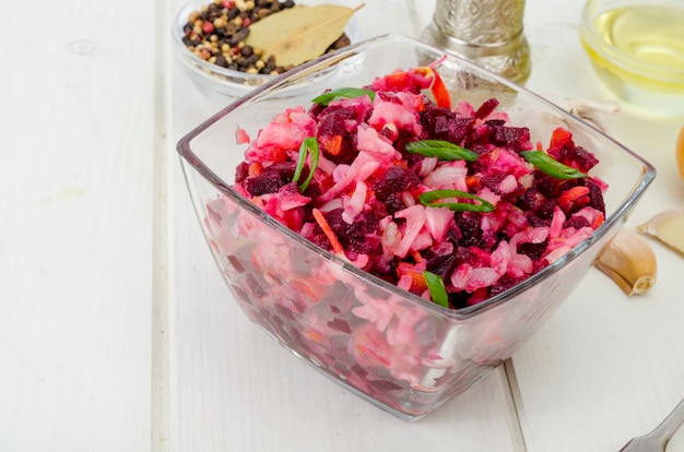 Groentesalade met bieten, kruiden, uien, knoflook op houten tafel