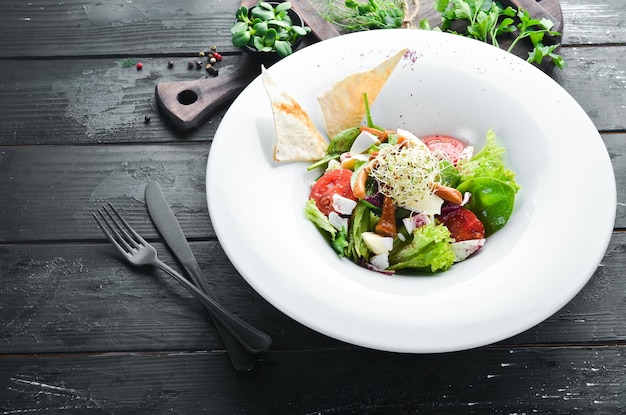 Groentesalade met brie, cherrytomaatjes en spinazie. Op de plaat. Bovenaanzicht. Vrije ruimte voor uw tekst. Rustieke stijl.