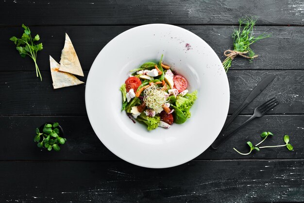 Groentesalade met brie-kaas, cherrytomaatjes en spinazie in het bord bovenaanzicht vrije ruimte voor uw tekst rustieke stijl