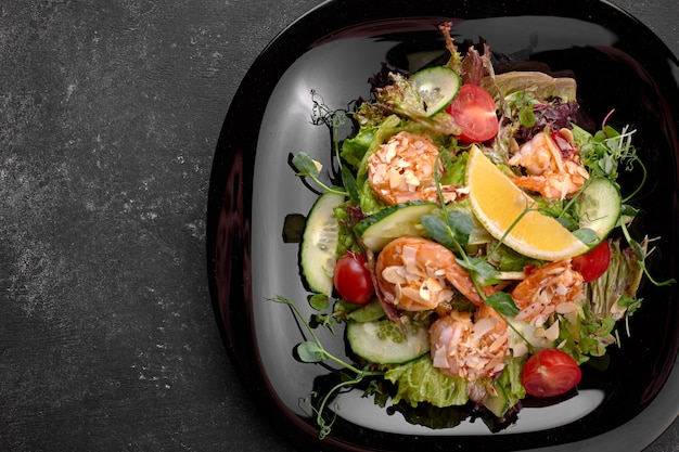 Groentesalade met garnalen, op een zwarte achtergrond