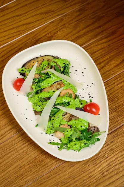 Groentesalade met gebakken aubergine op witte plaat op houten achtergrond