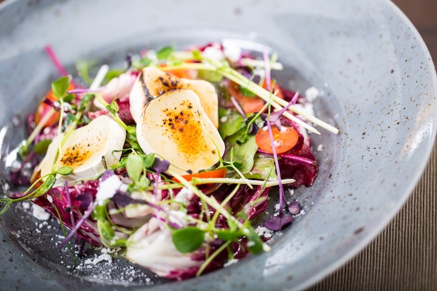 Groentesalade met geitenkaas en kruidendecoratie.