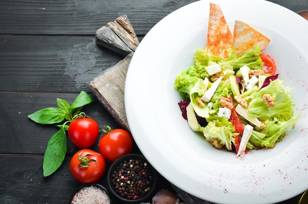 Groentesalade met kaas, olijven en kerstomaatjes. In de plaat. Bovenaanzicht. Vrije ruimte voor uw tekst. Rustieke stijl.