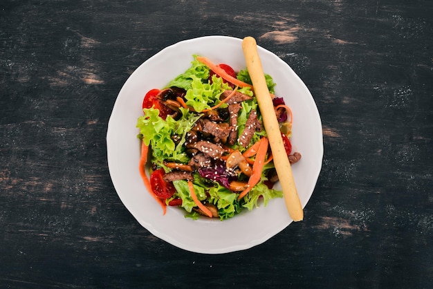 Groentesalade met kalfsvlees en champignons Op een zwarte houten achtergrond Bovenaanzicht Kopieer ruimte voor uw tekst