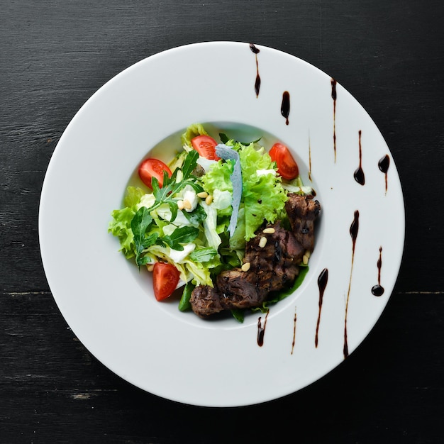 Groentesalade Met Kalfsvlees. Sla, kalfsvlees, pijnboompitten, cherrytomaatjes. Bovenaanzicht. Vrije ruimte voor uw tekst.