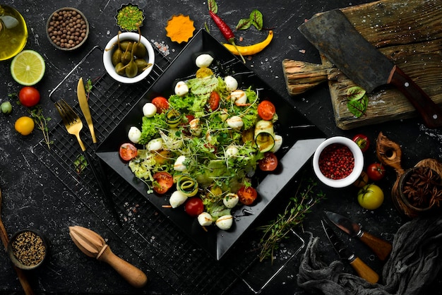 Groentesalade met mozzarellakaas Op een zwart bord Bovenaanzicht Eten Rustiek