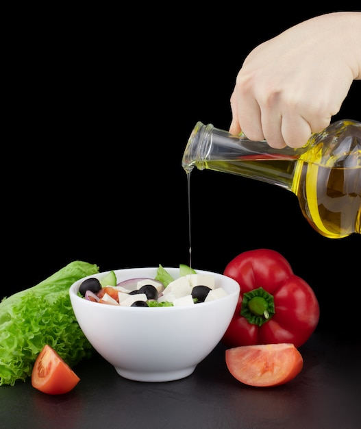 Groentesalade met olijfolie het gieten van een fles