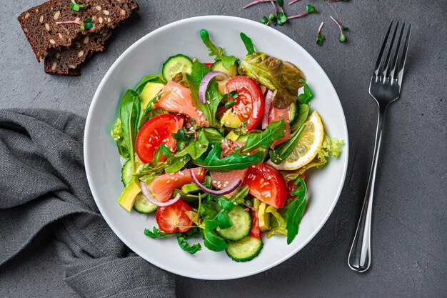 Groentesalade met zalm, verse kruiden en citroen op een donkere achtergrond Bovenaanzicht close-up Gezonde voeding