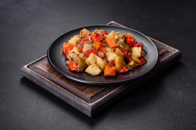 Groentestoofpot of ratatouille met aubergine tomaten zoete en hete pepers uien wortelen en kruiden in bord
