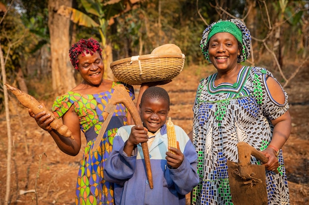 Groep Afrikaanse boeren heeft plezier in de velden, ze hebben schoffels in hun handen en ze zijn klaar om het veldkind te ploegen met de mand met gewassen op zijn hoofd