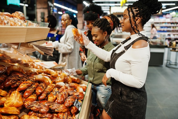 Groep Afrikaanse dames met winkelwagentjes in de buurt van gebakken producten in een supermarkt