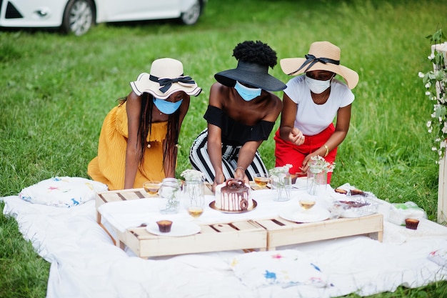 Groep afro-amerikaanse meisjes met gezichtsmaskers die verjaardagsfeestje vieren buiten met decor tijdens coronavirus pandemie.