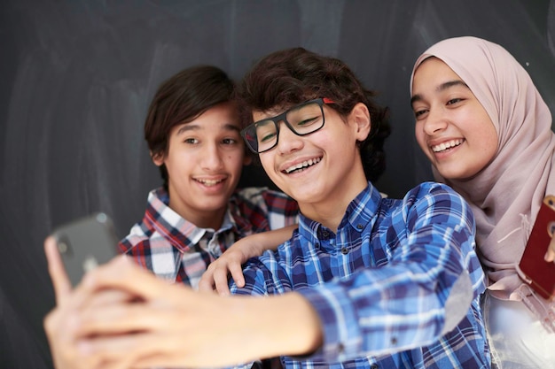 groep Arabische tieners die selfie-foto maken op smartphone met zwart bord op de achtergrond