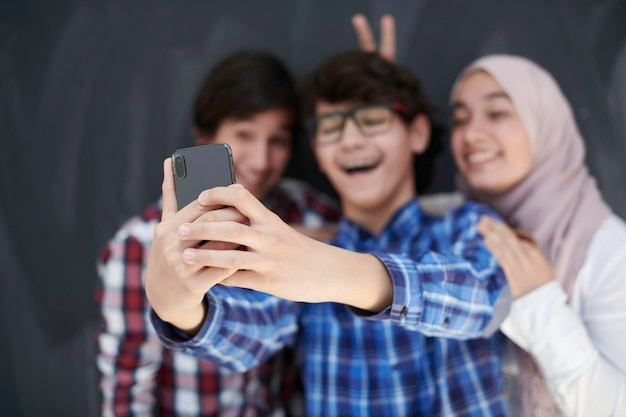 groep Arabische tieners die selfie-foto maken op smartphone met zwart bord op de achtergrond