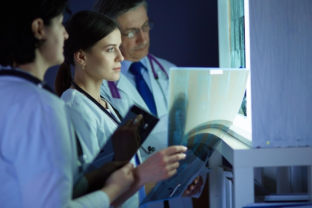 Groep artsen die röntgenfoto's in een kliniek onderzoeken en aan een diagnose denken