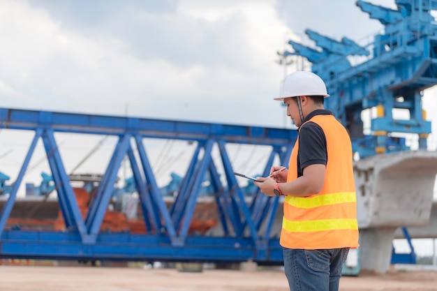 Groep Aziatische ingenieurs bespreken het werk op de bouwplaats in aanbouw Het aannemersteam bespreekt het ontwerp van de constructie Drie arbeiders werken buiten