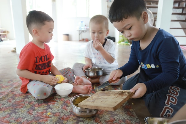 Groep Aziatische kinderen die eten bereiden en plezier hebben thuis, thuisschooler en onderwijsconcept.